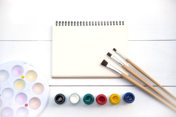 istock Artistic paintbrushes, placed on a drawing book with watercolors. 994069084