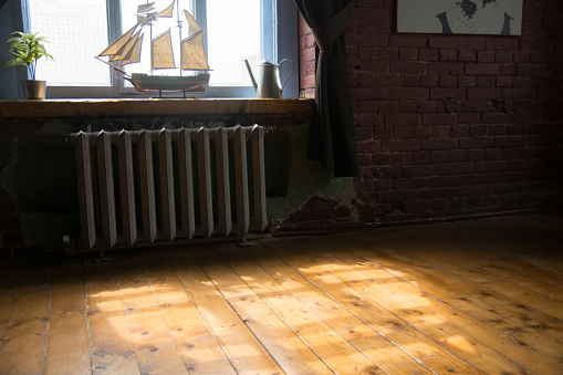 Interior of the room with a ship model on the windowsill and wooden floor.