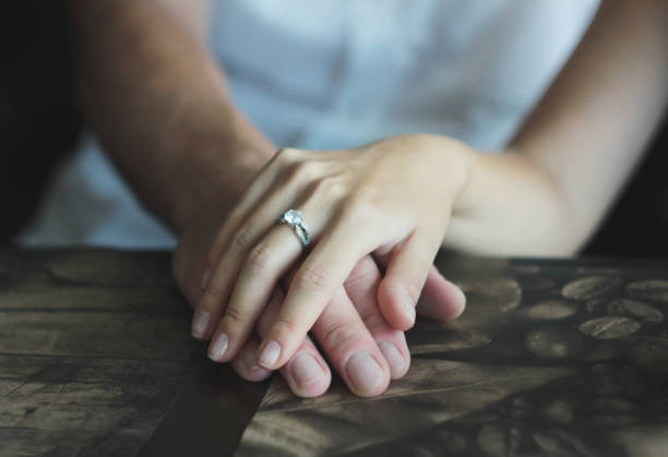 istock Woman's hand with an engagement ring on man's hand, date in the cafe 994087360