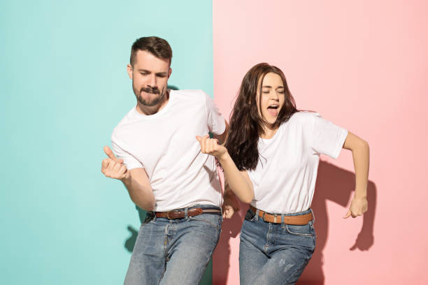 A couple of young man and woman dancing hip-hop at studio A couple of young funny and happy man and woman dancing hip-hop at studio on blue and pink trendy color background. Human emotions, youth, love and lifestyle concept live boy stock pictures, royalty-free photos & images