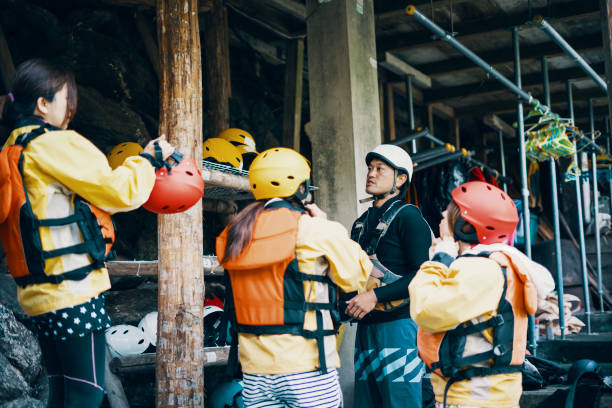 kleine gruppe von frauen, die versuchen auf helmen in vorbereitung für wildwasser-rafting - white water rafting outdoor pursuit rafting rapid stock-fotos und bilder