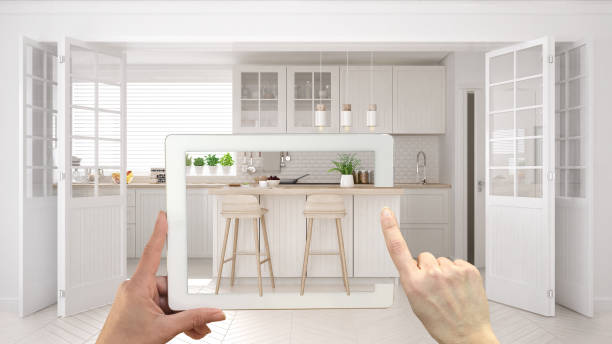 istock Augmented reality concept. Hand holding tablet with AR application used to simulate furniture and interior design products in real home, scandinavian kitchen with island 994099280