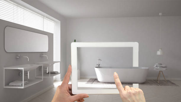 istock Augmented reality concept. Hand holding tablet with AR application used to simulate furniture and interior design products in real home, minimalist white bathroom 994099310