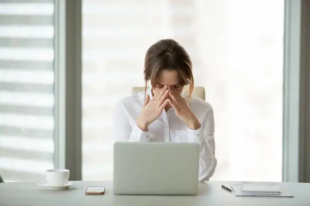 Frustrated businesswoman feels panic shock after business failure or bad news online sitting in office with laptop, stressed upset woman employee worried about bankruptcy, exhausted tired of overwork