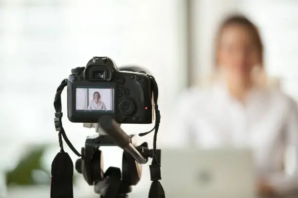 Photo of Professional dslr digital camera filming vlog of business woman vlogger