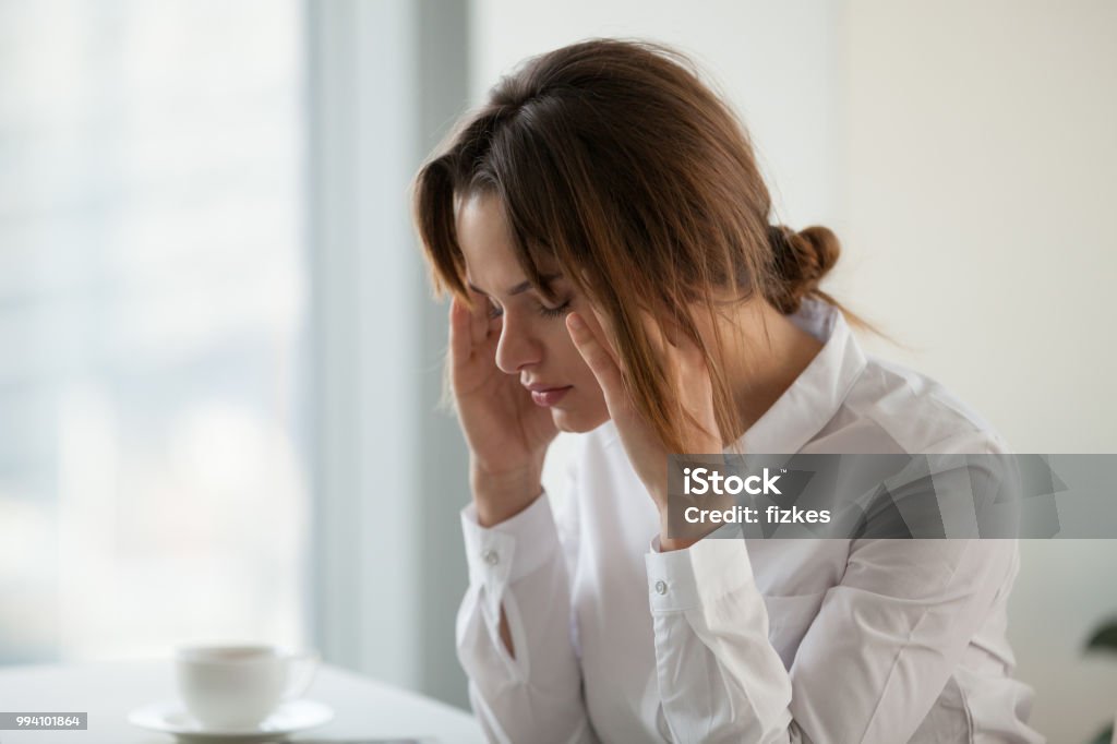 Tired exhausted businesswoman feeling strong headache at work touching temples Tired exhausted businesswoman having strong headache migraine at work touching massaging temples, stressed overworked woman feeling dizzy or fatigued, suffering from anxiety or panic attack in office Hormone Stock Photo