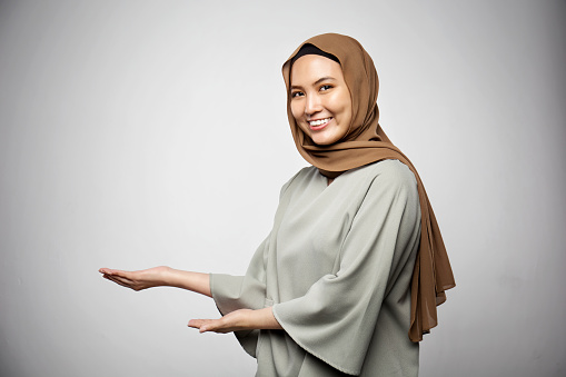 Muslim woman showing and presenting something in white background.