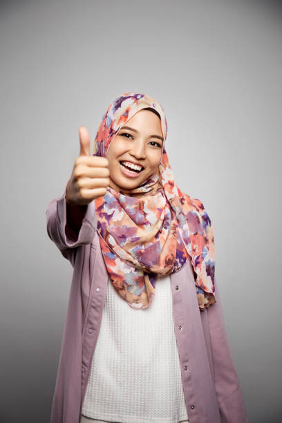 счастливая smilling мусульманская женщина показывая большие пальцы руки вверх жест. - women middle eastern ethnicity islam hijab стоковые фото и изображения