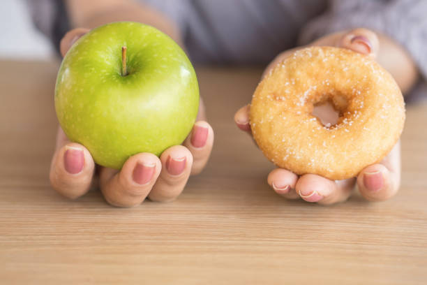 woman hands holding green apple and donut