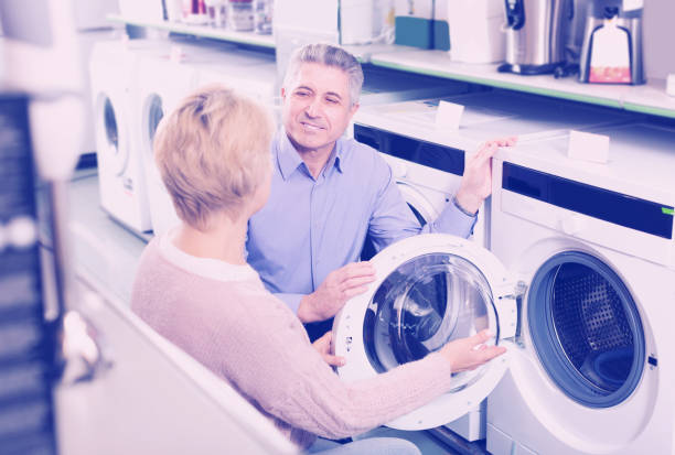 istock Husband with wife selecting modern washing machine 994112936