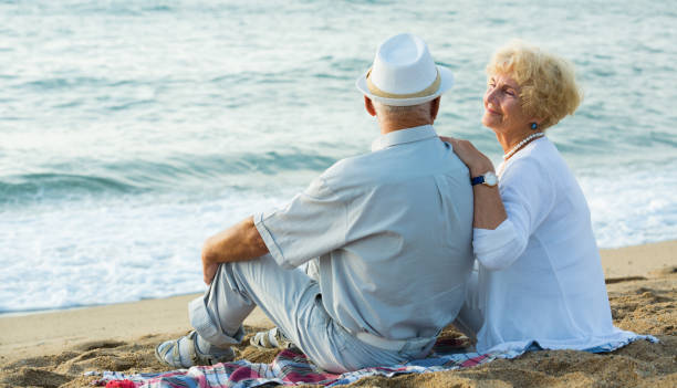 istock Mature man and woman sitting back on towel 994113210