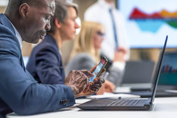 biznesmen za pomocą telefonu komórkowego w sali konferencyjnej - multi ethnic group concentration mobile phone using laptop zdjęcia i obrazy z banku zdjęć