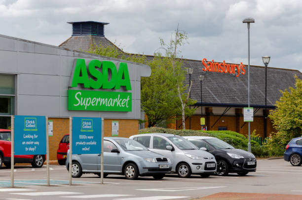 Asda and Sainsbury supermarkets have neighbouring stores in Flint Flint, UK: May 1, 2018: Asda and Sainsbury who have announced a potential merger with no store closures are neighbours in the North Wales town of Flint. "nCars in the Asda car park with the Sainsbury store at the side. asda photos stock pictures, royalty-free photos & images
