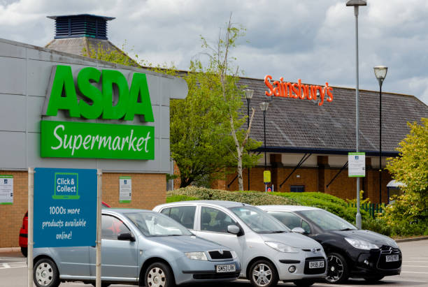 Asda and Sainsbury supermarkets are neighbours in the North Wales town of Flint. Flint, Wales, 01st May 2018. Asda customer cars parked in their car park under the shadow of the Sainsbury supermarket located uncomfortably nearby."nSainsbury and Asda have suggested in their initial comments about their potential merger that there will be no store closures. asda photos stock pictures, royalty-free photos & images