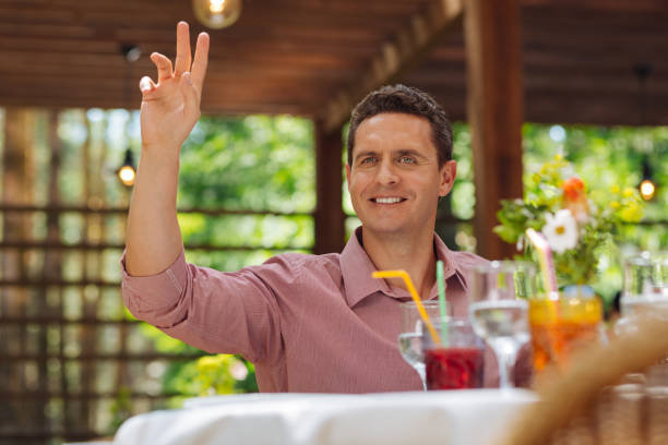 istock Appealing man lifting his hand sitting in restaurant 994125152