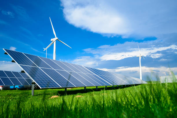 Solar energy panels and windmills against blue sky on summer day