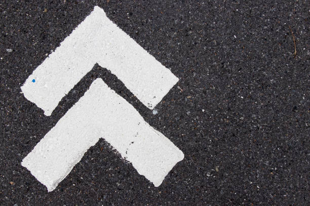 istock White painting in forward direction arrow symbol on black asphalt road background 994147714