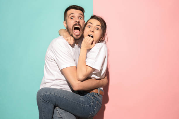 Portrait of the scared man and woman on pink and blue We are in awe. Fright. Portrait of the scared man and woman. Couple standing on trendy pink and blue studio background. Human emotions, facial expression concept. Front view terrified stock pictures, royalty-free photos & images