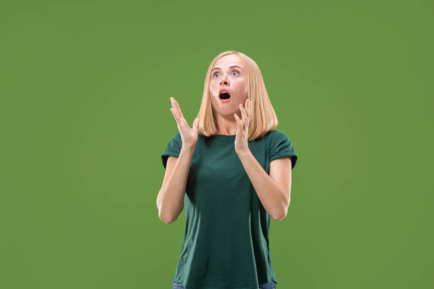 istock Beautiful woman looking suprised isolated on green 994155354