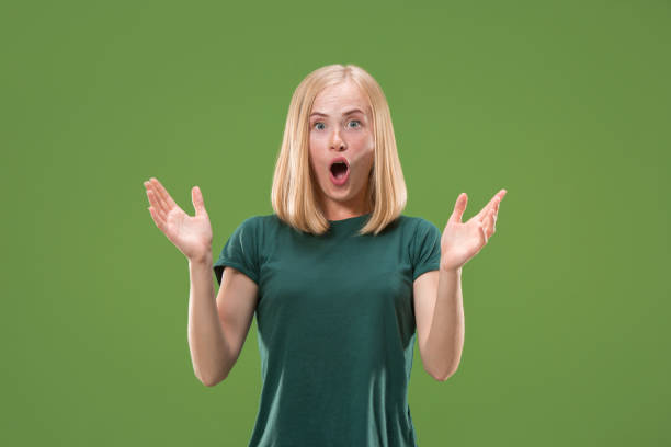 istock Beautiful woman looking suprised isolated on green 994155904