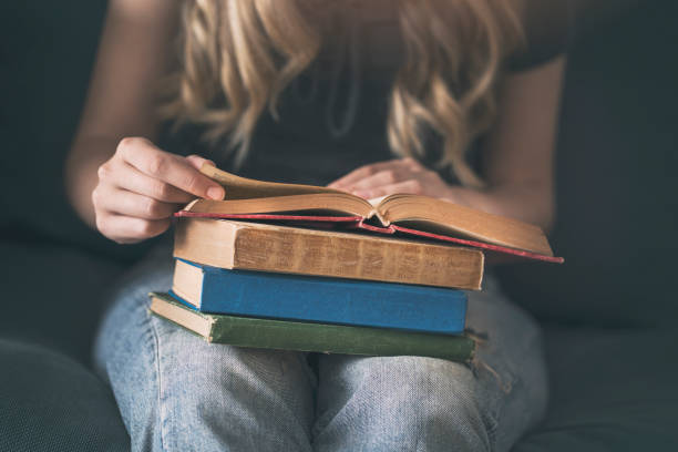 istock Young woman reading a book on a sofa 994156340