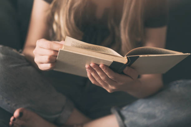 istock Young woman reading a book on a sofa 994156342