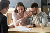 Excited couple sign purchase contract in Real Estate Agent office
