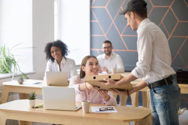 istock Delivery man giving pizza cardboard box to smiling employee 994164886