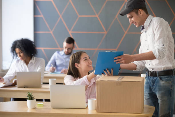 istock Deliveryman asking woman sign documents after package delivery in office 994164920