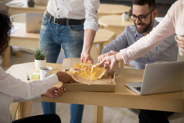 istock Happy colleagues enjoying shared pizza lunch in office together 994164922