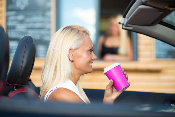 istock Young blond woman with drive-in caffe in a car 994167680