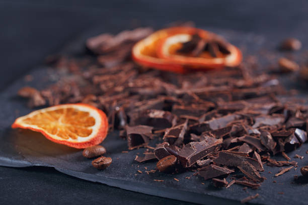 istock Dark chopping chocolate, black roasted coffee beans, dried lemon slices on dark background 994185314