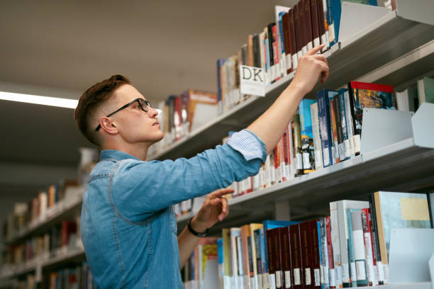 istock Man Looking For Book In Bookstore. Student In Library 994198050