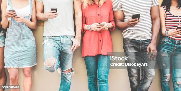 Group Of Millennial Friends Watching Smart Mobile Phones Teenagers Addiction To New Technology Trends Concept Of Youth Tech Social And Friendship Focus On Smartphones Stock Photo - Download Image Now