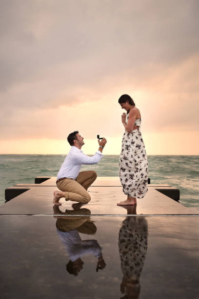 Getting down on one knee Full length shot of a handsome young man proposing to his girlfriend on the jetty at the beach life events photos stock pictures, royalty-free photos & images
