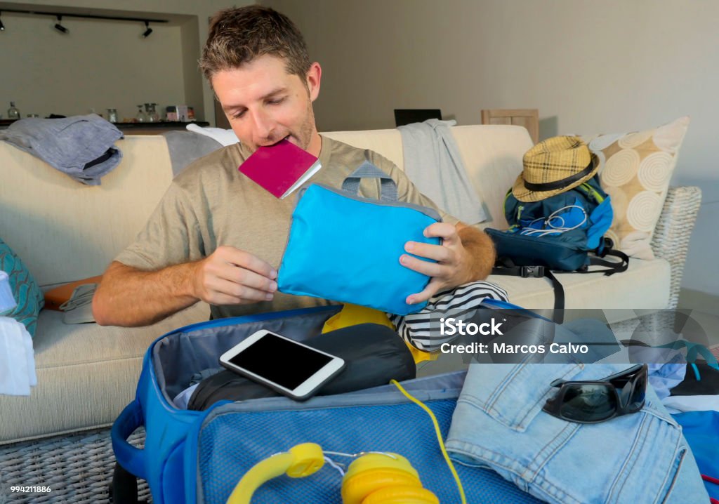 young attractive and happy man at home couch preparing travel back and packing suitcase folding clothes and organizing passport and things before leaving on holidays trip and travel concept 30-39 Years Stock Photo