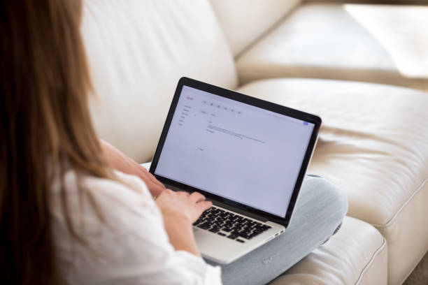 widok z tyłu na kobietę piszącą e-mail na laptopie w domu - quilt back zdjęcia i obrazy z banku zdjęć