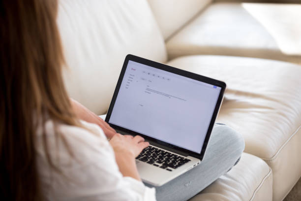 rear view at woman writing email on laptop at home - writing letter correspondence women imagens e fotografias de stock