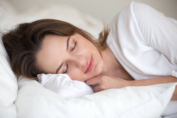 young woman sleeping well lying asleep in comfortable cozy bed - material data sheets imagens e fotografias de stock