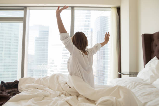 istock Rear view at woman stretching on bed waking up happy 994243638