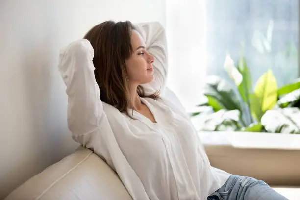 Photo of Relaxed woman resting breathing fresh air at home on sofa