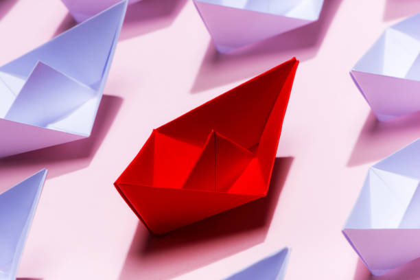 istock Leadership concept. Red paper ship leading among white 994254960
