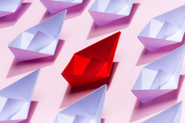 istock Leadership concept. Red paper ship leading among white 994255458