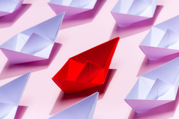 istock Leadership concept. Red paper ship leading among white 994255792