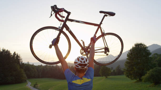 istock CLOSE UP: Ecstatic road biker lifting his bike over head while looking at sunset 994258428