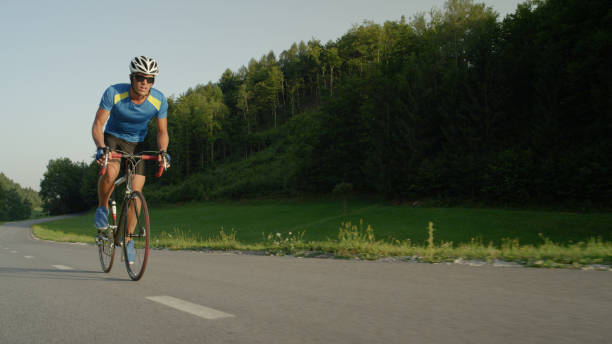 istock Professional biker goes fast through sunlit spring nature on cool road bicycle. 994258444