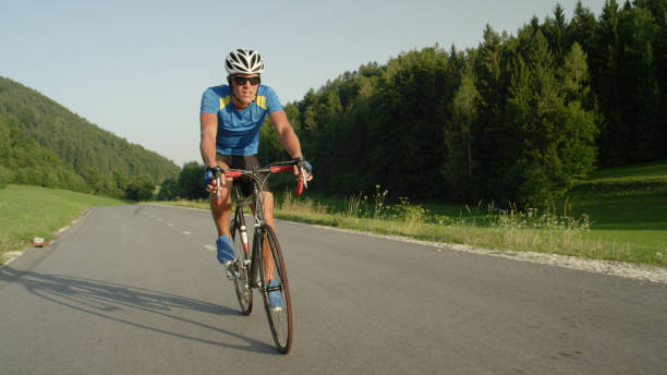 istock Professional male cyclist cruises down empty asphalt road on a sunny spring day. 994258446