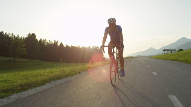istock LENS FLARE: Athletic young sportsman pedals down an empty sunlit asphalt road. 994258464