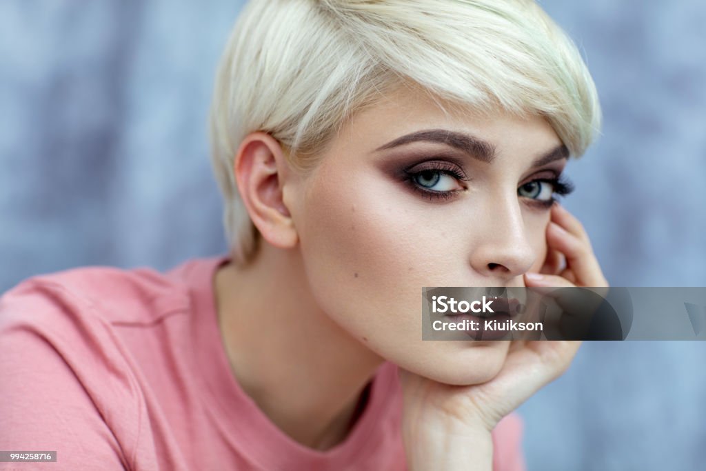 Portrait photo of young female model with short blond hair Portrait of young female model in fashionable make up with short hair looking at camera Short Hair Stock Photo