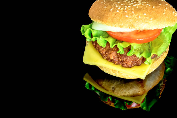 istock Big fat hamburger with fresh vegetables with reflection isolated on black background 994259970